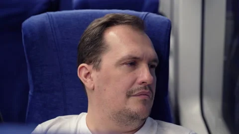 Millennial man thinking, looking at window of moving suburban train. Travelling Stock Footage 169413024