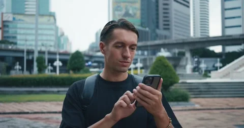 Millennial man tourist with backpack using mobile phone while explore city Stock Footage 250590585