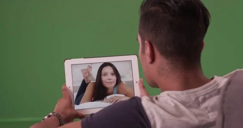 Millennial man video chatting or having a facetime conversation on green screen Stock Footage 79371533
