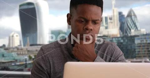 Millennial office worker reading emails in the city on laptop computer Stock Photos