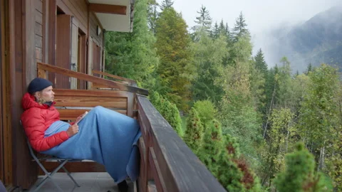 Millennial read book on balcony of mountain hotel Stock Footage 135145925