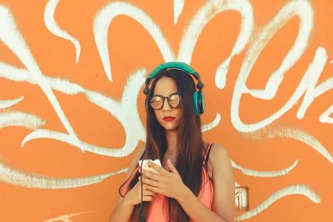 Millennial  using her mobile phone to listen music in her headphones Stock Photos