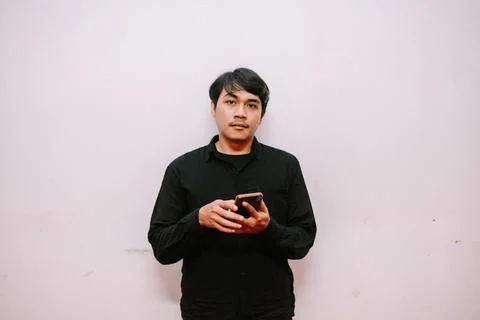 Millennial Using Phone Against Light Wall, Holding Smartphone Foto stock