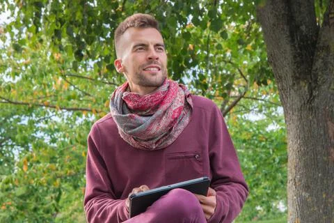 Millennial using tablet pc in park with green trees Stock Photos