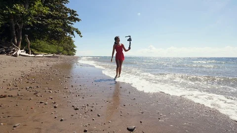 A millennial vlogger walking on the beach and recording vlog for social media Stock Footage 118470153