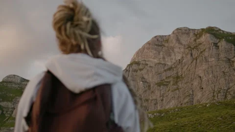 Millennial woman with dreadlocks and backpack looking at big mountain Stock Footage 148148558