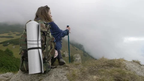 Millennial woman on mountain excursion standing high on cliff looking the dis Stock Footage 86218310