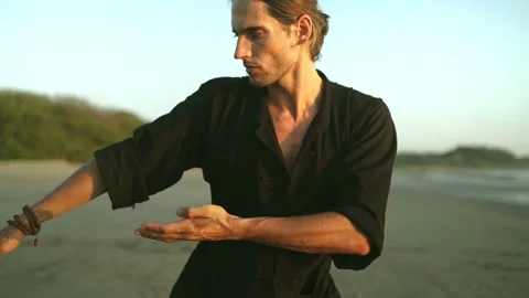 Millennial young fit man practice Qi gong, Tai Chi yoga on beach, summer. Stock Footage 187220964