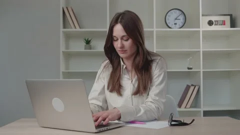 Millennial young lady in sand-colored shirt laughing is in correspondence on a Video stock 154398002