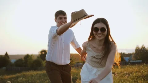 Millennials couple have fun playing with hat, running, catching each other Stock Footage 122559873