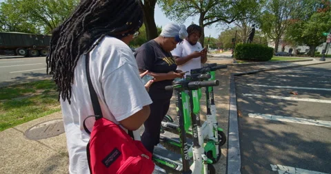 Millennials use their phone to rent scooters on the street in Washington D.C. Stock Footage 138829415