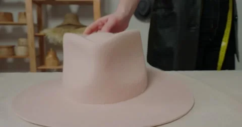 Milliner puts finished felt hat on white table in workshop Stock Footage 207453573