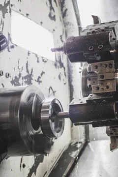 A milling cutter in a CNC machine cuts a metal workpiece that rotates Stock Photos