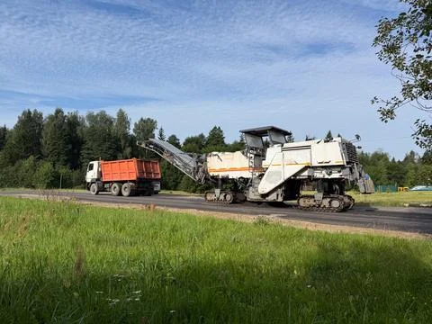 Milling machine loading into dump truck, concept of roadworks, with copyspace Stock Photos