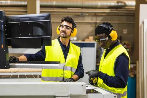 Millworkers operating cnc machine in carpentry workshop Stock Photos