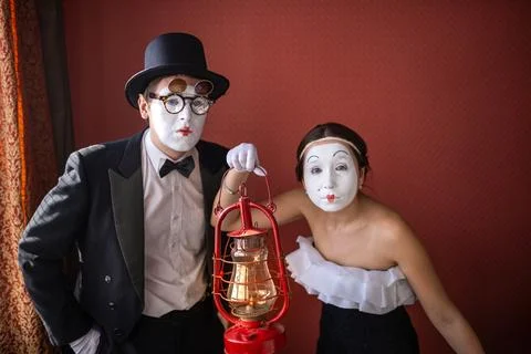 Mime couple looking forward behind a vintage red lantern Stock Photos