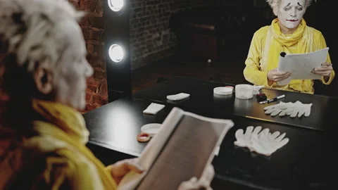 Mime sits at table against mirror repeating lines in script Stock Footage 192397192