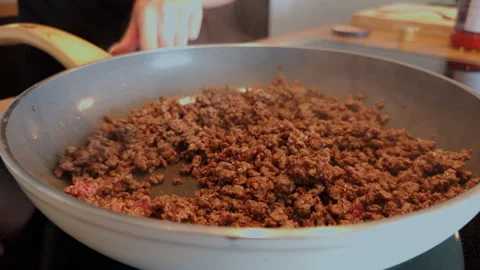 Minced beef being browned and stirred in a frying pan on the stove. Shows Stock Footage 341317772
