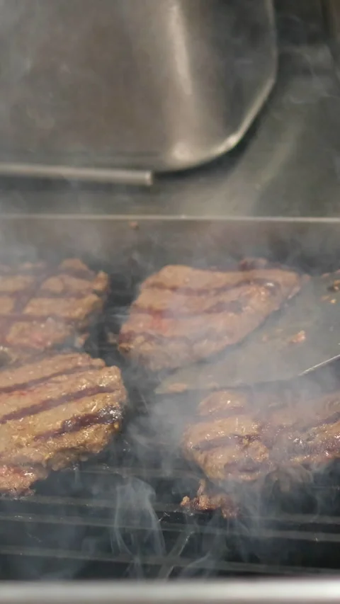 Minced beef burger meat patties cooking on hot black electric grill surface Stock Footage 323929946