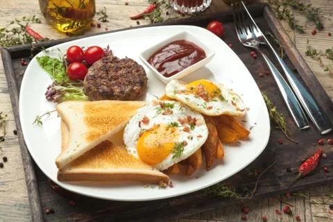 Minced beef on the grill with  fried eggs, crisp and toast. Foto stock