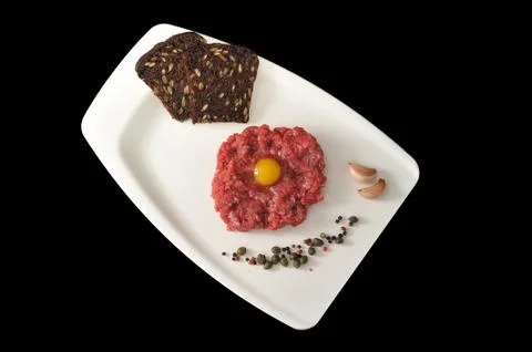 Minced beef with raw egg on a white Board tray on black background Stock Photos