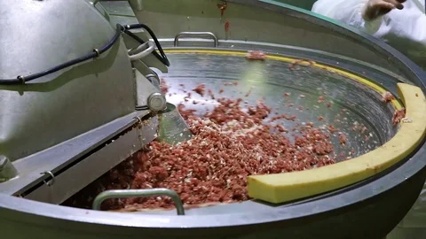 The minced meat is automatically stirred in a large bowl. An additive is poured  Stock Footage 129305915