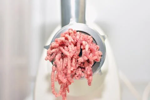 Minced meat production process in an electric meat grinder Stock Photos