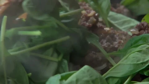 Minced meat with spinach leaves is fried in a frying pan Stock Footage 303424218