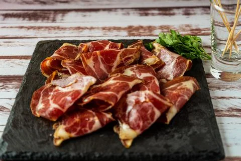 Minced view of an exquisite fetas de bondiola or raw pickled pork on a black  Stock Photos