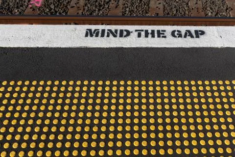 The mind gap warning at a train station, with yellow studs for the blind Stock Photos