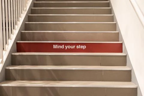 Mind your step precaution message printed on step on staircase Stock Photos