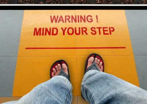Mind your step signage on a train platform with a man standing Stock Photos