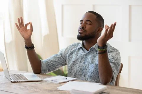 Mindful african american guy relaxing during remote working. Stock Photos