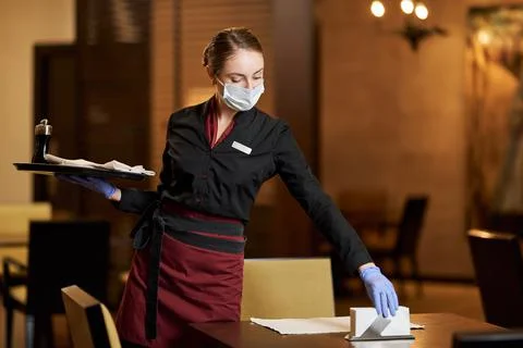 Mindful cafe worker using mask while serving the table Stock Photos