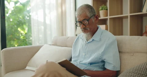 Mindful elderly Asian man in glasses reading a book for lifelong learning Vídeos de archivo 336057708