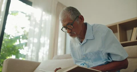 Mindful elderly Asian man in glasses reading a book for lifelong learning Stock-Footage 336057714