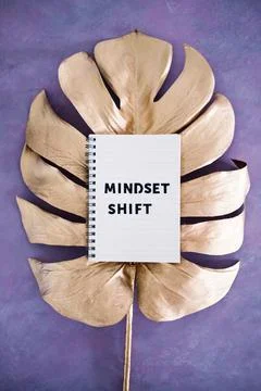 Mindset Shift notepad on top of golden leaf on pink background, psychology an Stock Photos