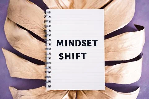 Mindset Shift notepad on top of golden leaf on pink background, psychology an Stock Photos