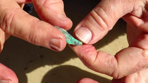 Miner inspecting rock for rough opal content Stock Footage 80749454