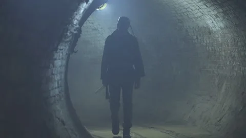 Miner with a pickaxe walks in a dark and dusty tunnel 스톡 동영상 253288349