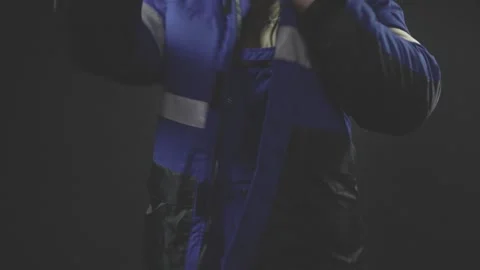 Miner puts on overalls, jacket and boots. Shooting with studio light Stock Footage 161547699