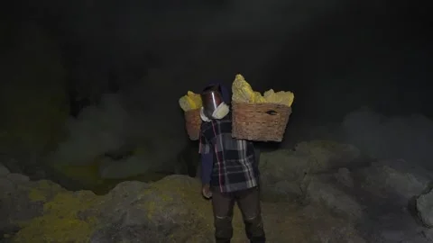 Miner working inside Kawah Ijen volcano crater at night in East Java, Indonesia Stockbeeldmateriaal 313712997