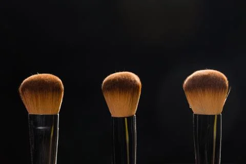 Mineral makeup and objects concept - Three makeup brushes over dark background Stock Photos