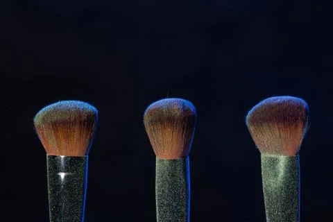 Mineral makeup and objects concept - Three makeup brushes with blue powder over Foto stock