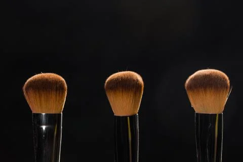 Mineral makeup and objects concept - Three makeup brushes over dark background Foto stock
