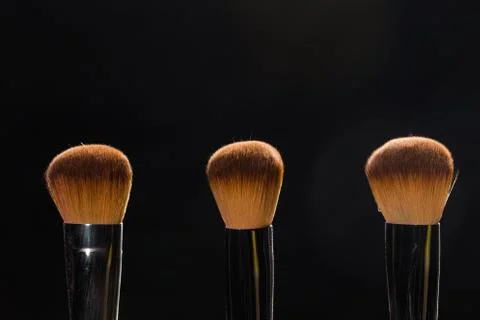 Mineral makeup and objects concept - Three makeup brushes over dark background Foto stock