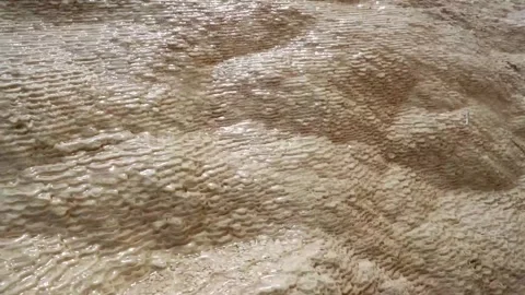 Mineral spring water flowing over textured travertine deposits Stock Footage 345036982