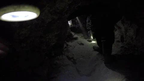 Miners exploring a dark underground tunnel with headlamps Stock Footage 337408661