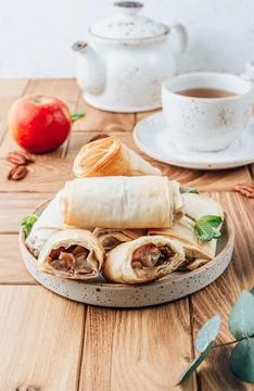 Mini apple strudel with pecans and mint on wooden table. Viennese pastry. Stock Photos