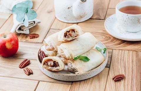 Mini apple strudel with pecans and mint on wooden table. Viennese pastry. Stock Photos